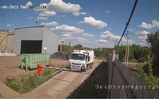 Кадр камеры на весовой: мусоровоз на въезде у шлагбаума, номер скрыт